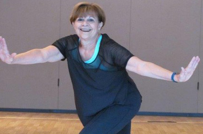 middle aged female breast cancer survivor Carol Fee shows off her dance moves at Zumba.